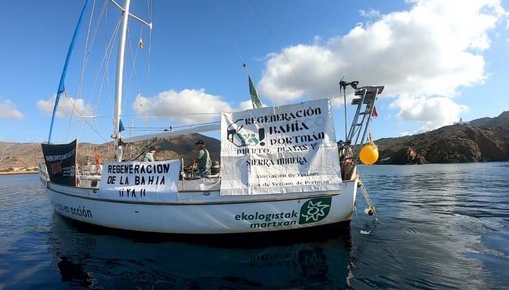 El Velero de Ecologistas en Acción despliega en Portmán pancartas para exigir su regeneración y contra la macro-terminal de El Gorguel